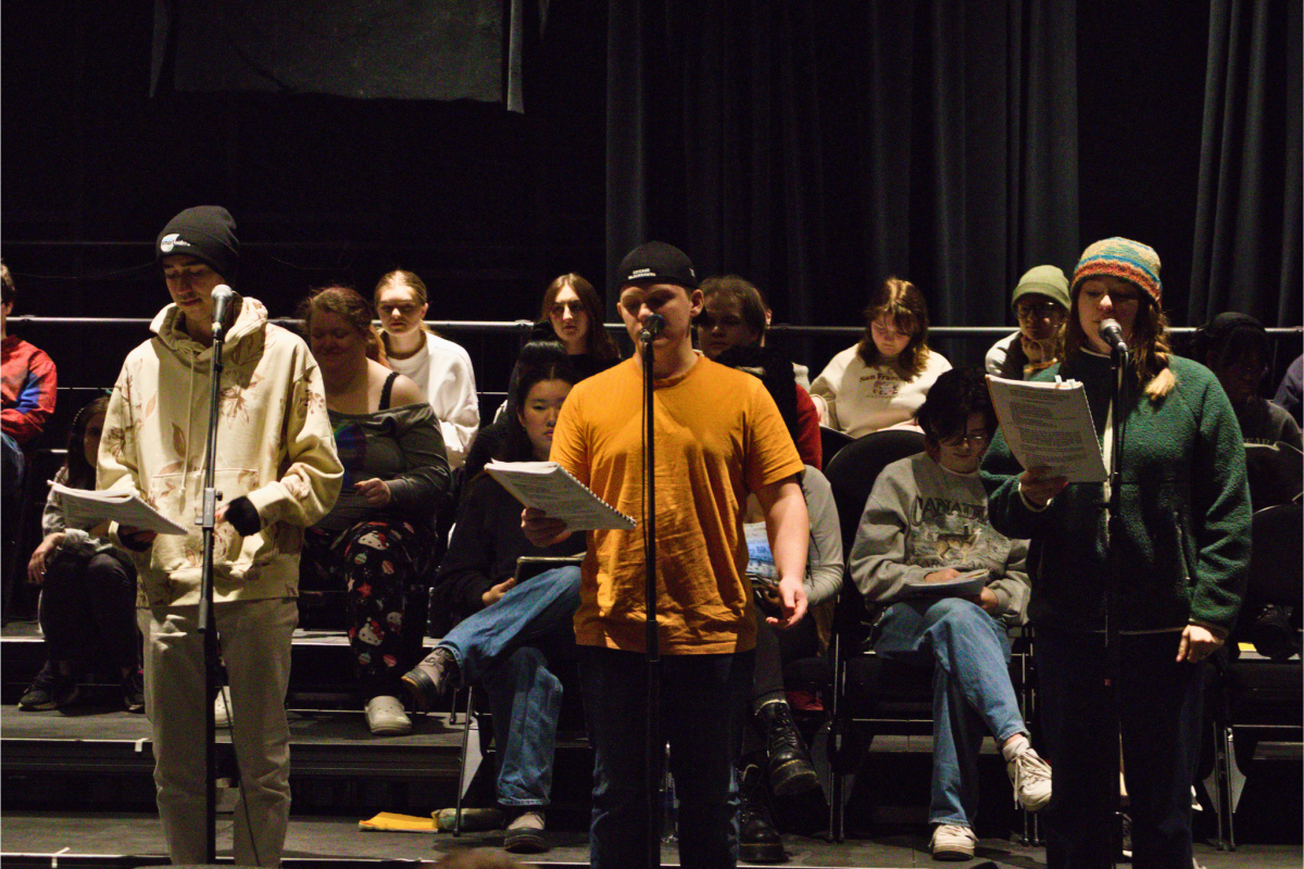 University of Guelph student ensemble members rehearsing for the Little Shop of Horrors production. Front row, left to right: Luka Burazin, Bachelor of Commerce student; Liam Wesley, Music major and Alyssa Boyle, Music major. Behind them, the rest of the student ensemble fills the stage.